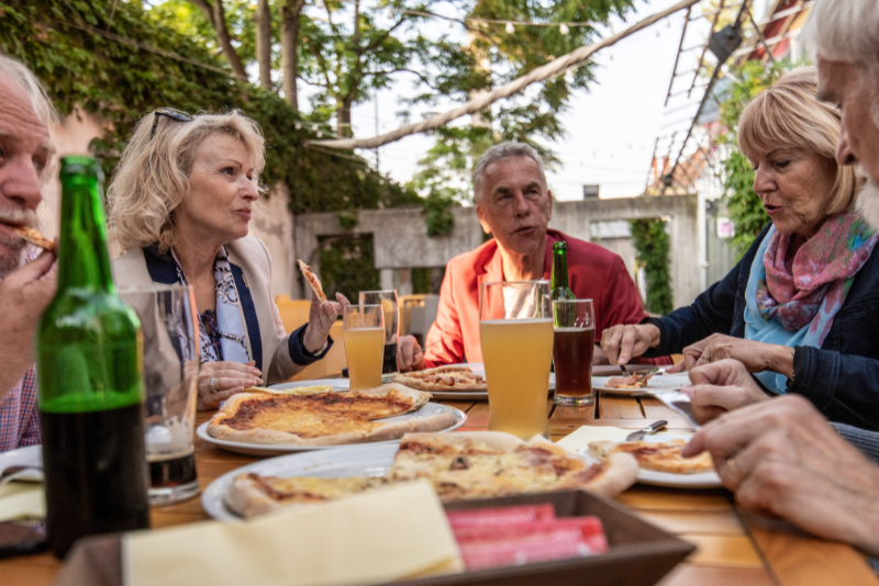 persone sedute a tavola all'aperto che mangiano