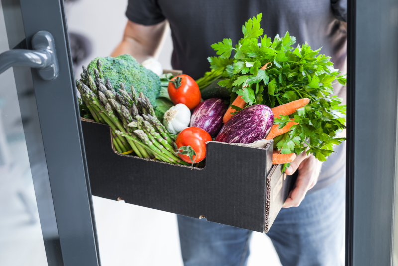un ragazzo che tiene una cassetta di verdure